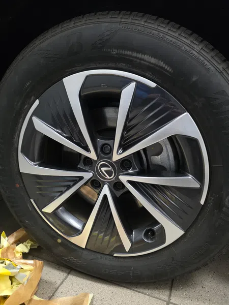Close-up of a Lexus car wheel with black and silver alloy rim and Bridgestone tire on tiled floor.