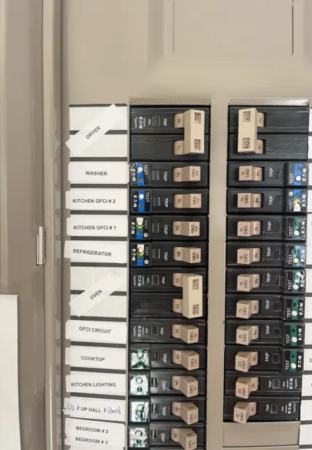 Electrical breaker panel with labeled switches for dryer, washer, kitchen appliances, and bedroom circuits.