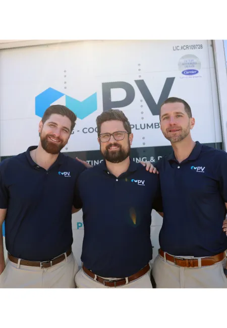 Three men in matching navy blue PV company shirts standing together outside in front of a service truck on a sunny day