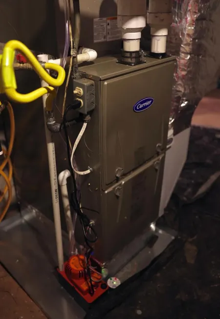 Residential Carrier furnace unit with pipes, wiring, and basement setup for heating and ventilation system.