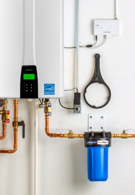 Modern tankless water heater installation with copper pipes and filtration system.