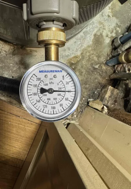 Close-up of a Measureman pressure gauge showing psi and kPa readings attached to industrial equipment.