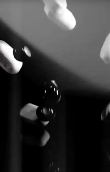 Black and white image of multiple falling pills captured in mid-air with reflective surface below.