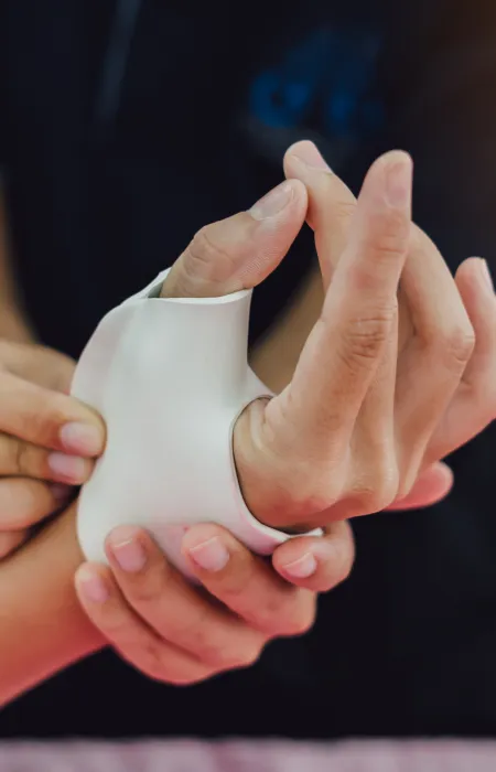 Close-up of a person applying a wrist brace to another person's hand for support and injury prevention.