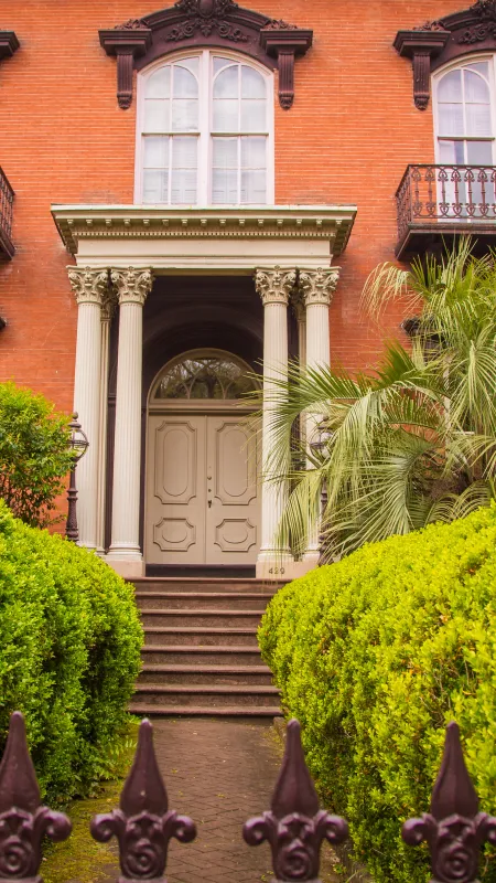 a large house with a large front yard and palm trees with Mercer House in the background