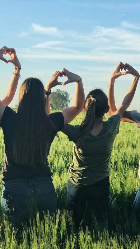 a group of women holding their hands up in a grassy field