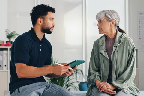 Healthcare professional consulting an elderly woman in a medical office discussing health concerns.