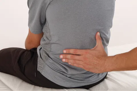 Chiropractor providing back treatment to patient sitting on medical table in clinic