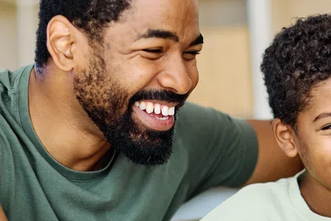 Happy father and son smiling and looking at a laptop screen together at home