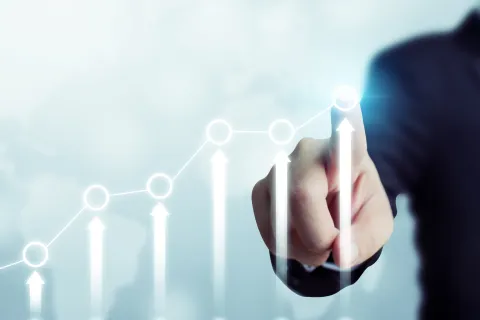 Businessman pointing at rising arrows and graph showing business growth and success increase