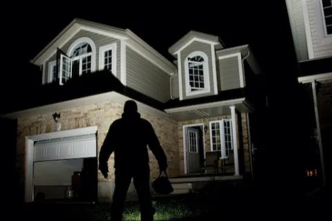 a thief walking in front of a house