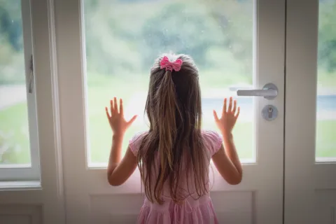 a girl with her hands up in front of a window