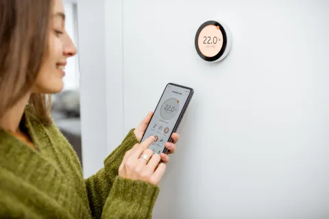 a woman controlling a thermostat through a phone