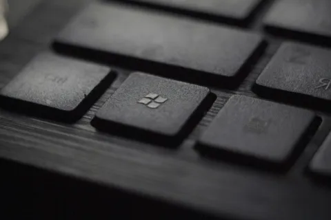 Close-up of black keyboard keys focusing on the Windows key with textured surface and blurred background.