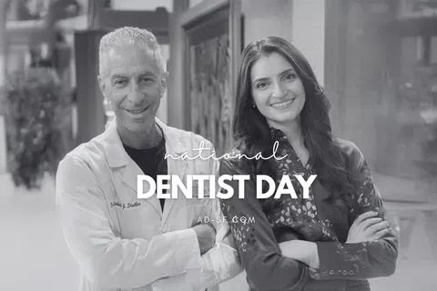 Smiling male dentist in white coat and female colleague celebrating National Dentist Day together indoors.