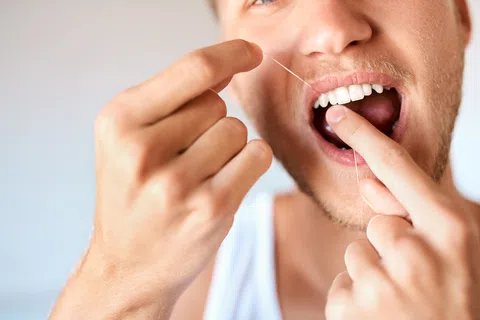 Close-up of a man flossing his teeth with dental floss for oral hygiene care