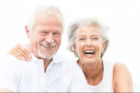 Happy elderly couple smiling and embracing each other outdoors with bright natural light background
