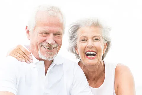 Smiling elderly couple with white hair enjoying time together wearing white tops on bright background