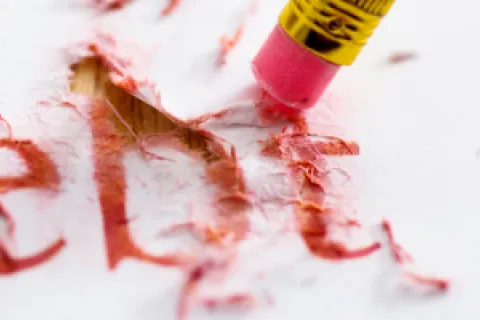 Pink eraser removing red text spelling 'Debt' on white paper shredding the word.