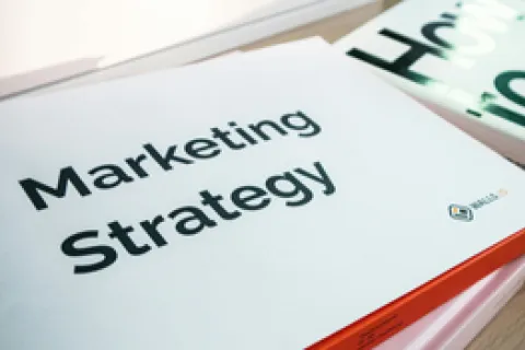 A book titled Marketing Strategy lying on a wooden table next to another book partially visible.