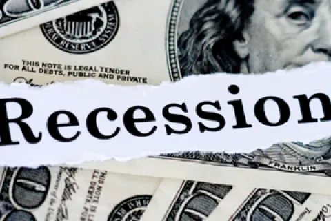 Torn paper with Recession Proof text overlaid on scattered US hundred dollar bills background.