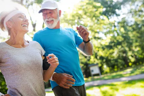 Active seniors jogging together in a sunny park, promoting fitness and joy in later life.