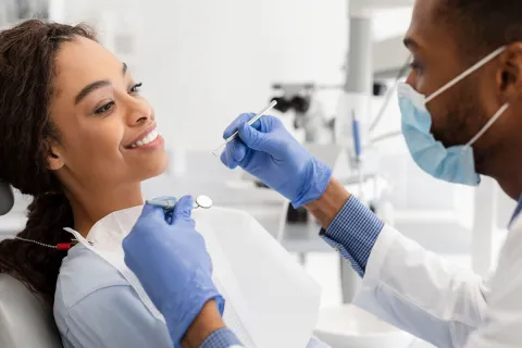 A dentist examining a smiling patient in a modern dental clinic setting.
