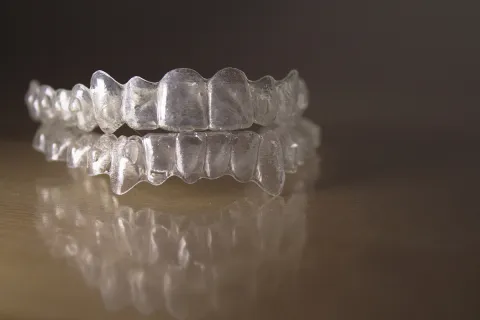 Close-up of transparent dental aligners on a reflective surface, showcasing their clear design.