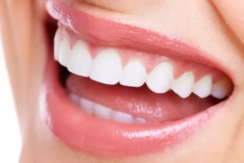 Close-up of a smiling mouth with white teeth and glossy lips, showcasing dental health and confidence.