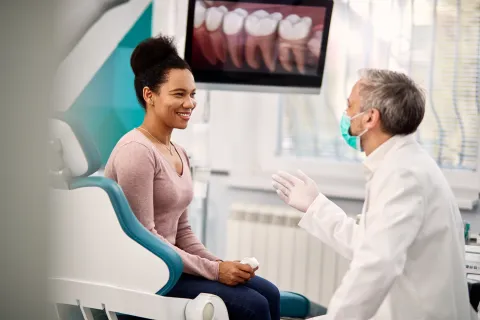 Dentist consulting with a smiling patient in a modern dental office environment.