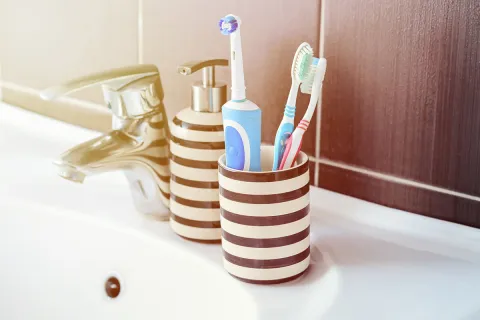 A modern bathroom setup featuring toothbrushes and a toothbrush holder by a sink.