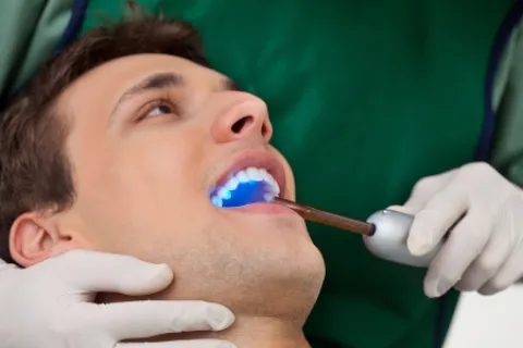 Dental professional using a blue light treatment on a patient in a dental clinic.