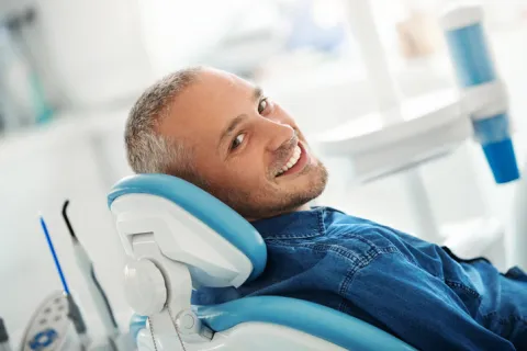 Smiling man comfortably seated in a dental chair, showcasing a friendly dental office atmosphere.