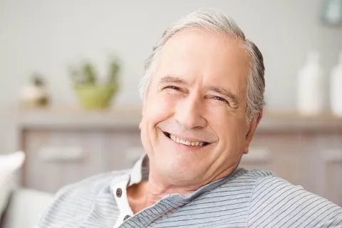 Smiling senior man relaxing at home, conveying warmth and happiness in a cozy environment.