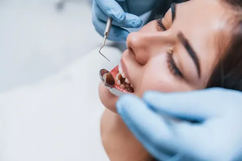 Dentist examining a patient's teeth with tools during a dental check-up.