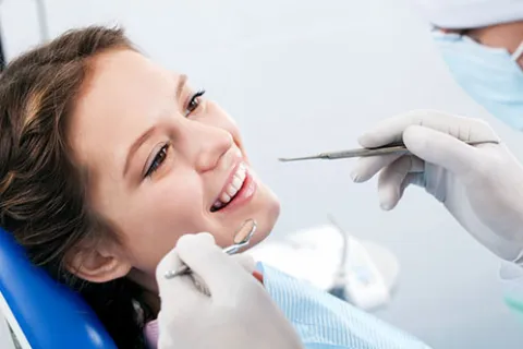 Patient smiling during a dental checkup with dentists tools in view.