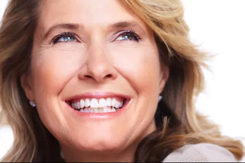 Smiling middle-aged woman with long blonde hair and blue eyes, exuding happiness and confidence.