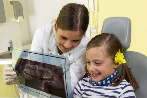 Dentist showing a young girl her dental X-ray with a smile in a dental office