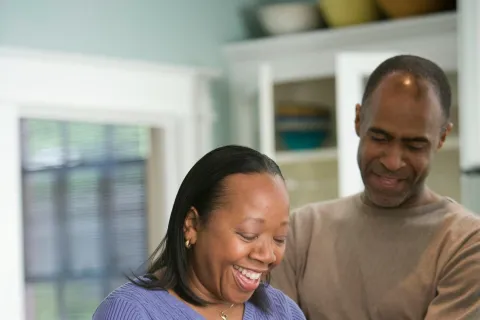 Happy couple preparing vegetables together in a bright kitchen, smiling and enjoying cooking time.