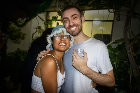 Happy couple smiling and hugging at an outdoor evening party surrounded by plants and lights
