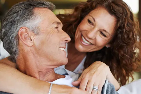 A happy couple sharing a warm, intimate moment while smiling at each other indoors.