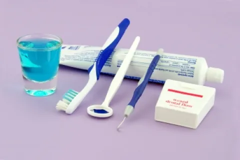 Dental care essentials including toothpaste, toothbrush, floss, and mouthwash on a purple background.