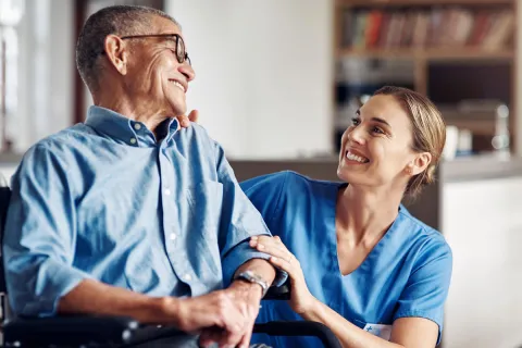 Healthcare professional smiling at elderly patient in a caring environment.