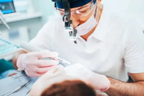 Dentist performing a dental procedure on a patient in a clinical setting with modern equipment.
