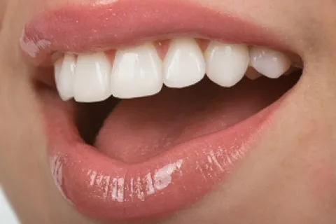 Close-up of a smiling mouth showing bright white teeth and glossy lips.