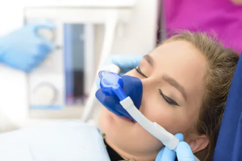 Patient receiving dental sedation with a mask in a clinical setting.