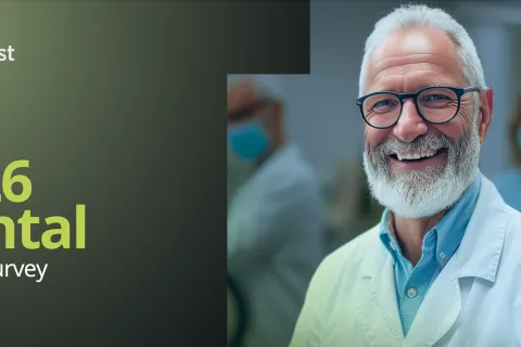 Smiling senior male dentist in white coat with team in background for 2026 dental salary survey report.