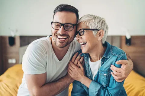 Happy man and woman laughing together in a cozy indoor setting, showcasing warmth and joy.