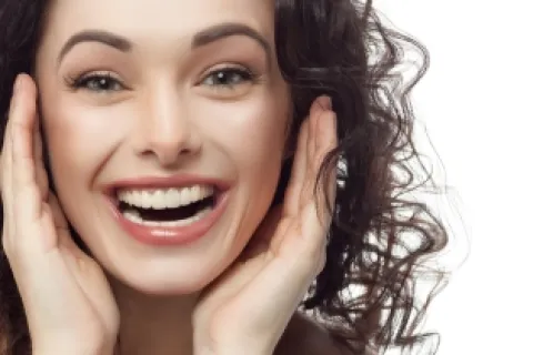 Smiling woman with curly hair expressing joy and positivity, highlighting her radiant smile.