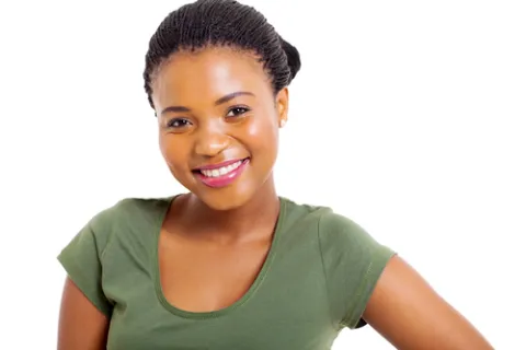 Smiling young woman in green shirt with braided hair posing against white background.
